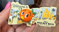 decorative magnet with cartoon character and text, against a blurred background.