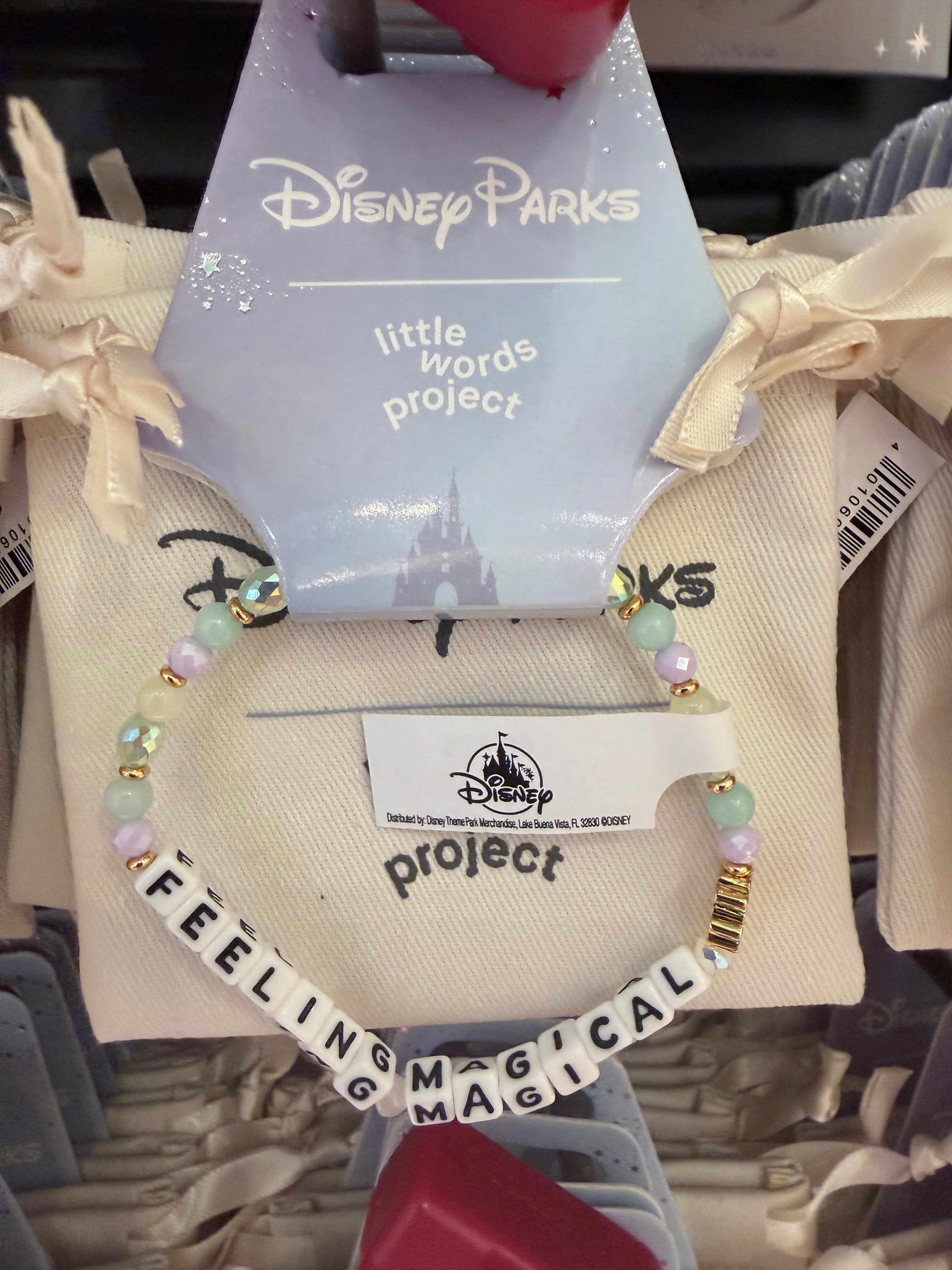 Bracelet with 'Feeling Magical' text and colorful beads on a display with Disney Parks and 'little words project' tags.