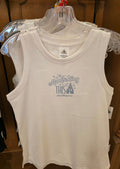 White tank top with blue text and graphics on a hanger against a wooden background