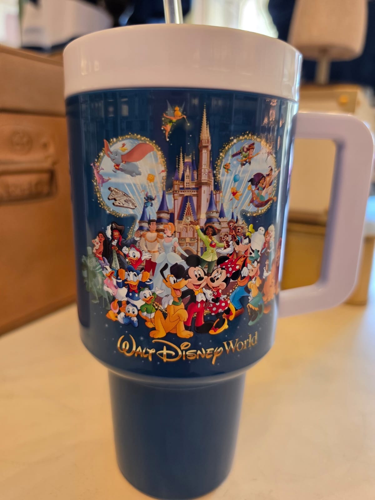 Blue tumbler with Disney characters and castle design on a white background