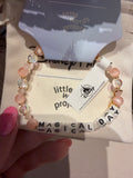Bracelet with 'MAGICAL DAY' beads held over a 'little words project' card.